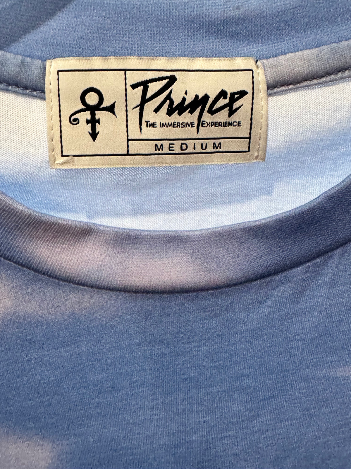 Official Prince merchandise blue sky and white clouds all-over print crew neck t-shirt size medium featuring the iconic Love Symbol on the inner neck label.