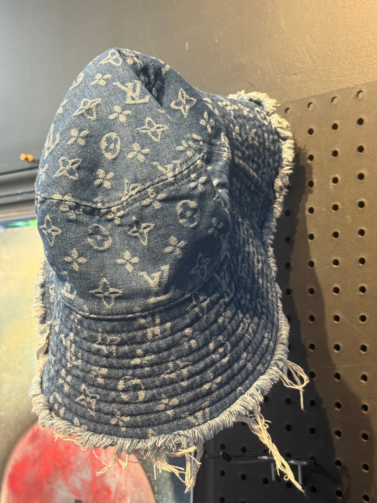 LV Monogram Denim bucket hat features a blue monogram pattern and frayed edges