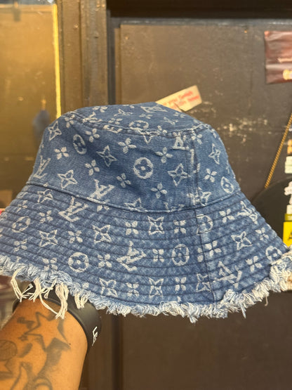 LV Monogram Denim bucket hat features a blue monogram pattern and frayed edges