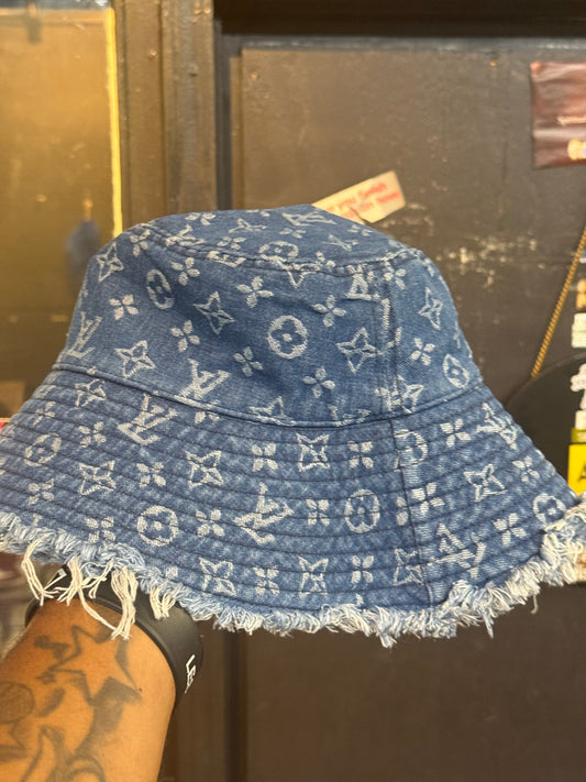 LV Monogram Denim bucket hat features a blue monogram pattern and frayed edges